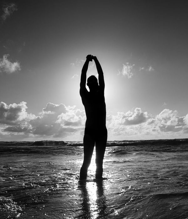 Man stretching outdoors at sunrise, looking calm and composed.